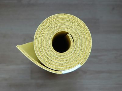 Eco-friendly green yoga mat rolled on the floor.