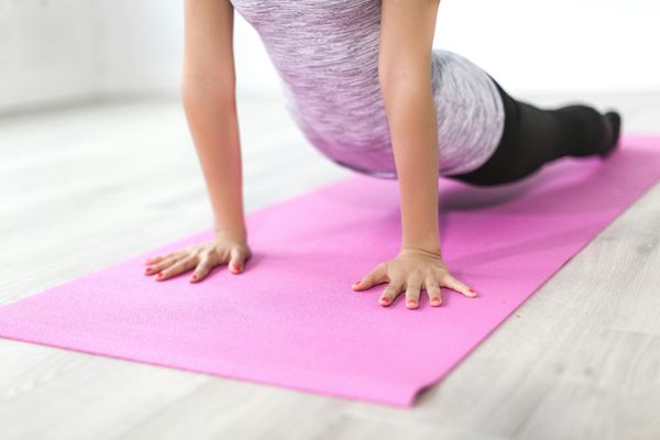 Person doing side stretch on a yoga mat in a forest.